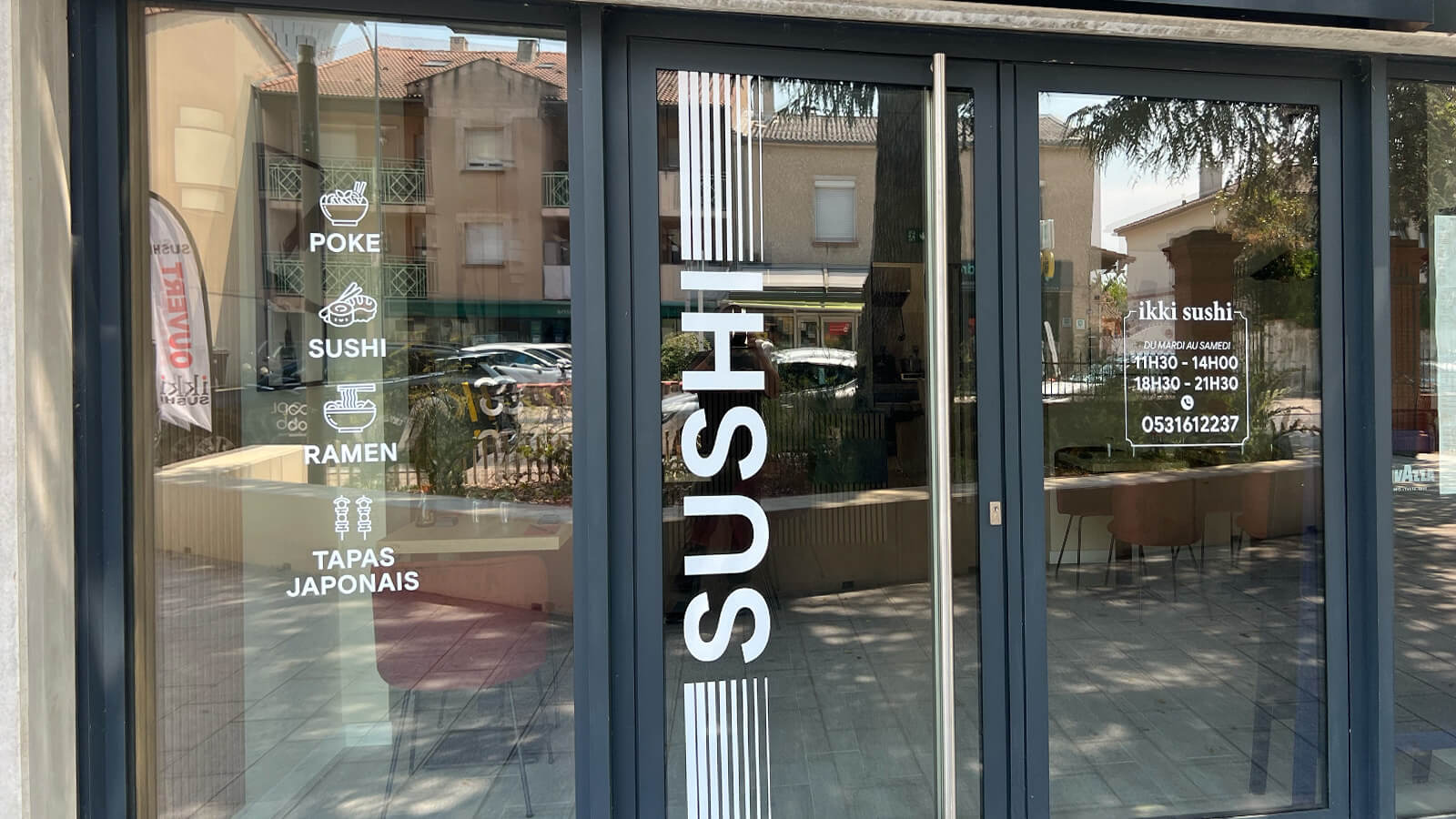 Lettrage adhésif posé sur une vitrine de commerce